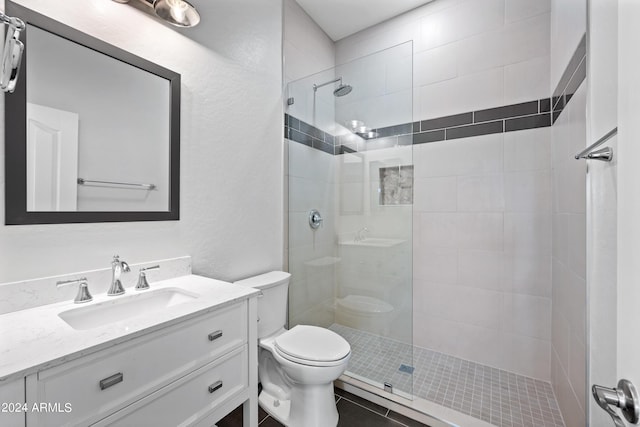 bathroom featuring a walk in shower, a textured wall, vanity, and toilet