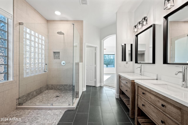 bathroom with two vanities, a stall shower, tile patterned flooring, and a sink