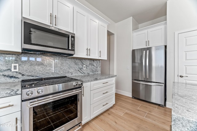 kitchen with light stone counters, white cabinets, light wood finished floors, appliances with stainless steel finishes, and tasteful backsplash