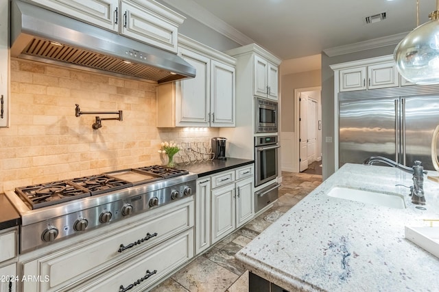 kitchen with tasteful backsplash, crown molding, sink, built in appliances, and white cabinets