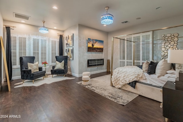 bedroom with dark hardwood / wood-style flooring, heating unit, and a notable chandelier