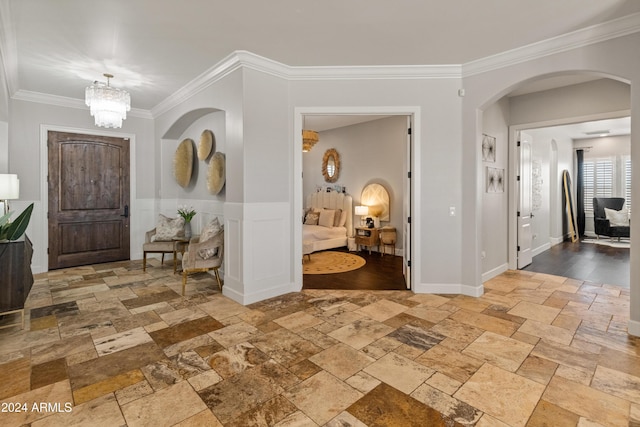 foyer entrance with a chandelier and crown molding