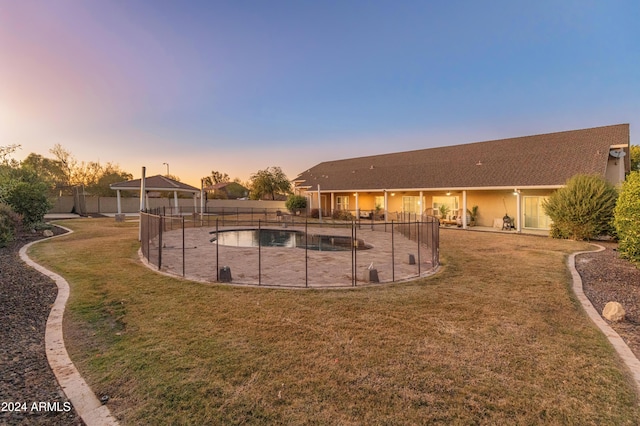 pool at dusk featuring a lawn