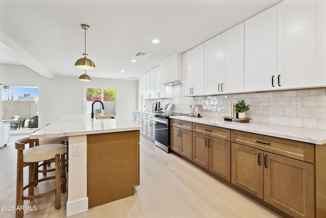 6761 E Juniper Ave, Scottsdale, AZ 85254 - kitchen with tasteful backsplash, stainless steel range oven, white cabinetry, and visible vents