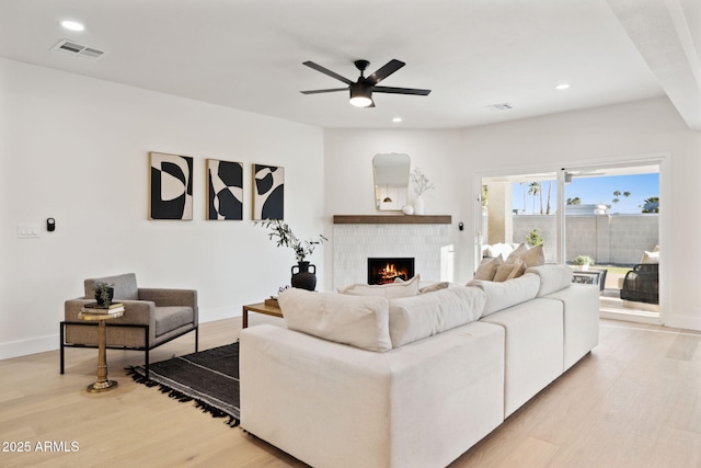 6761 E Juniper Ave, Scottsdale, AZ 85254 - living area with light wood-style floors, a ceiling fan, a warm lit fireplace, visible vents, and recessed lighting