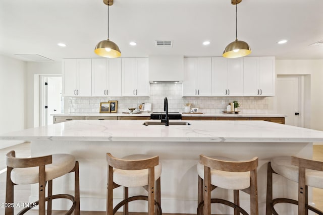 6761 E Juniper Ave, Scottsdale, AZ 85254 - kitchen with a sink, visible vents, backsplash, and a breakfast bar area