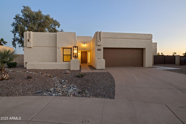 6761 E Juniper Ave, Scottsdale, AZ 85254 - pueblo revival-style home with an attached garage, driveway, stucco siding, and fence