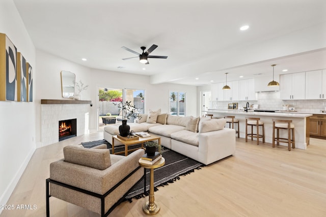 6761 E Juniper Ave, Scottsdale, AZ 85254 - living room with baseboards, a warm lit fireplace, recessed lighting, a ceiling fan, and light wood finished floors
