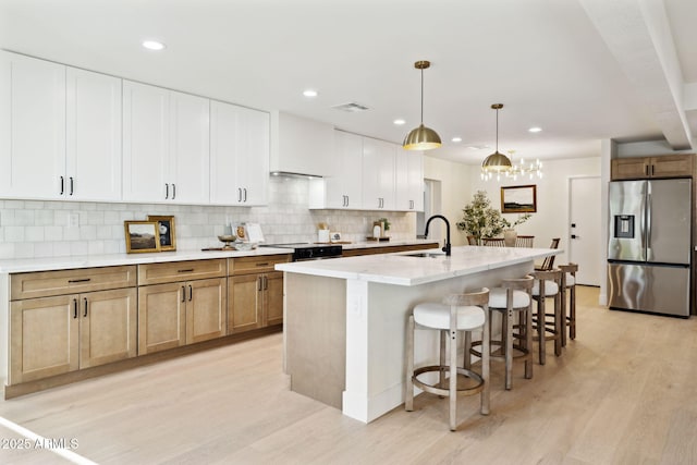 6761 E Juniper Ave, Scottsdale, AZ 85254 - kitchen featuring light wood-style floors, stainless steel refrigerator with ice dispenser, a sink, black range with electric cooktop, and decorative backsplash