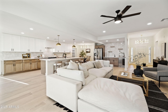 6761 E Juniper Ave, Scottsdale, AZ 85254 - living area featuring visible vents, light wood-style floors, recessed lighting, ceiling fan with notable chandelier, and beverage cooler