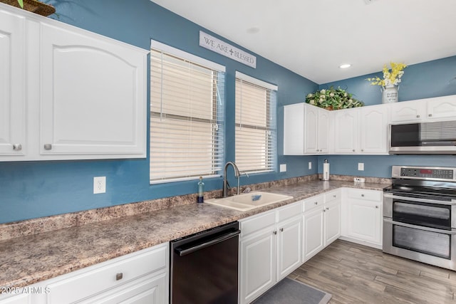 kitchen featuring white cabinetry, dishwasher, sink, and range with two ovens