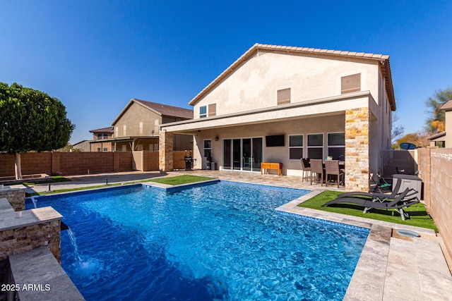 back of house featuring a fenced in pool, pool water feature, and a patio area