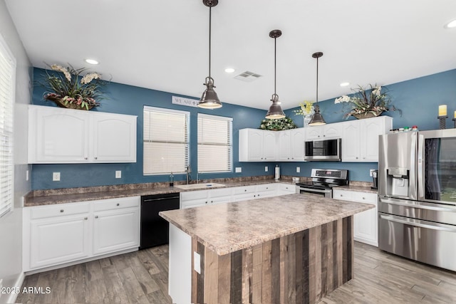 kitchen featuring pendant lighting, sink, appliances with stainless steel finishes, white cabinets, and a kitchen island