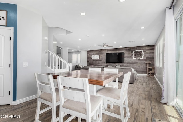 dining area with hardwood / wood-style flooring, ceiling fan, and wood walls