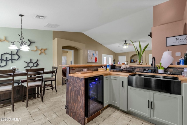 kitchen with wine cooler, hanging light fixtures, lofted ceiling, and light tile patterned flooring