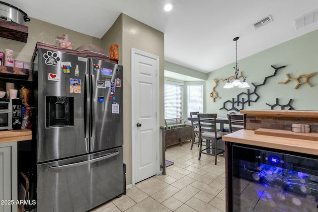 kitchen featuring butcher block countertops, hanging light fixtures, stainless steel refrigerator with ice dispenser, a notable chandelier, and light tile patterned flooring