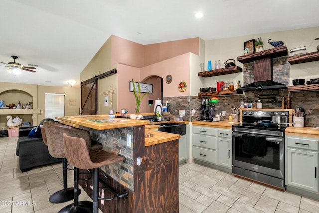 kitchen featuring sink, tasteful backsplash, wood counters, stainless steel range with electric cooktop, and a barn door