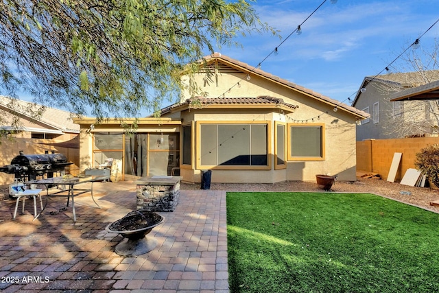 back of house featuring a fire pit, a patio area, and a lawn