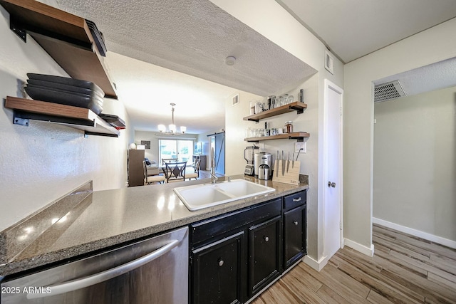 kitchen featuring sink, stainless steel dishwasher, a notable chandelier, light hardwood / wood-style floors, and a textured ceiling