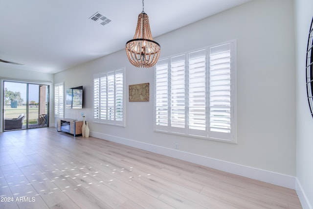 unfurnished living room with light hardwood / wood-style flooring and a chandelier