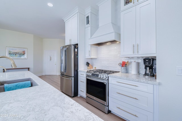 kitchen with backsplash, premium range hood, sink, appliances with stainless steel finishes, and white cabinetry