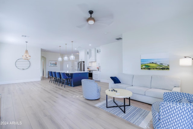 living room featuring ceiling fan, light wood-type flooring, and sink