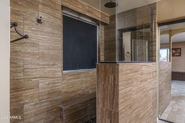 bathroom featuring tile walls and a tile shower