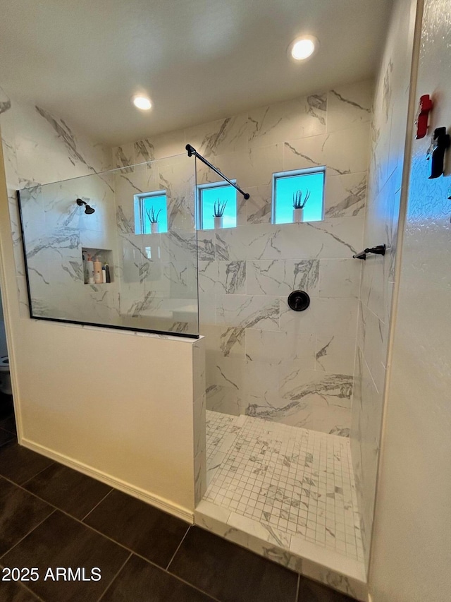 bathroom featuring tiled shower and tile patterned flooring