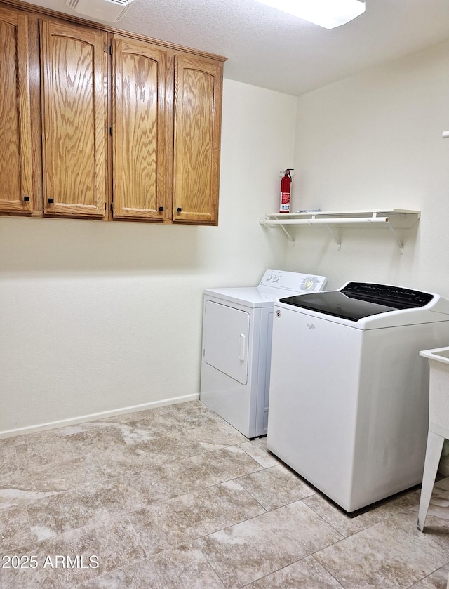 clothes washing area featuring washer and dryer and cabinets