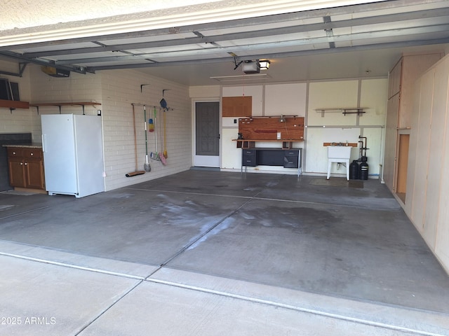 garage with a garage door opener, white refrigerator, and sink