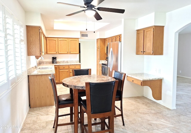 dining area featuring sink, ceiling fan, and a tray ceiling