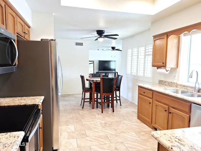 kitchen featuring sink, ceiling fan, light stone counters, and appliances with stainless steel finishes