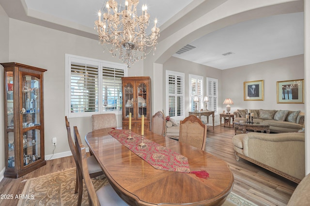 3125 W Desert Ln, Laveen, AZ 85339 - dining space featuring arched walkways, a chandelier, and light wood-style flooring