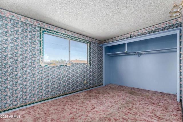 unfurnished bedroom featuring wallpapered walls, carpet flooring, a closet, and a textured ceiling