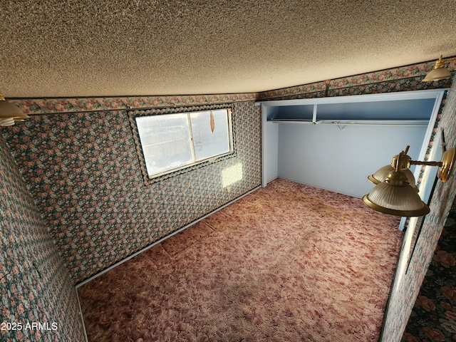 unfurnished bedroom with a textured ceiling, carpet flooring, and wallpapered walls