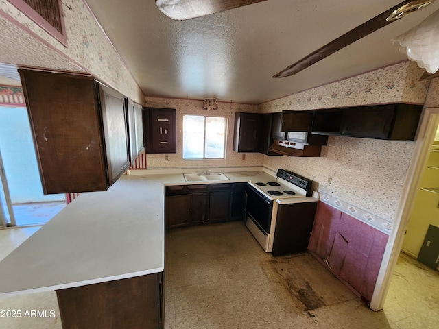 kitchen with electric range, a sink, wallpapered walls, light countertops, and light floors