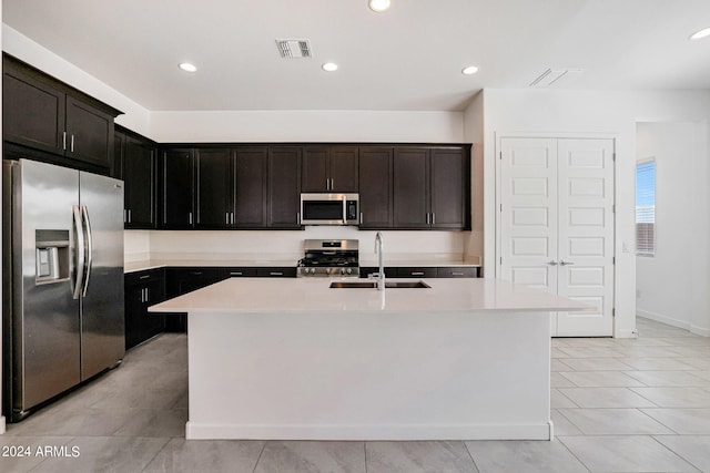 kitchen with dark brown cabinetry, light tile floors, an island with sink, stainless steel appliances, and sink