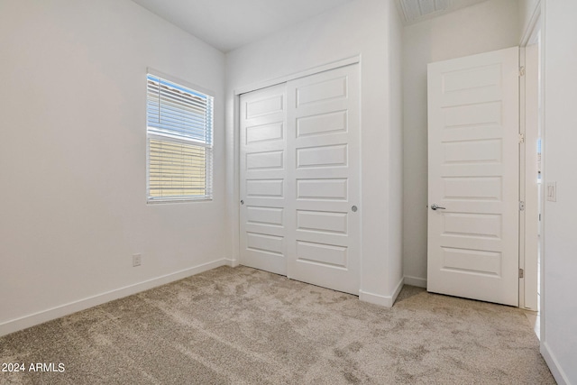 unfurnished bedroom with light carpet and a closet