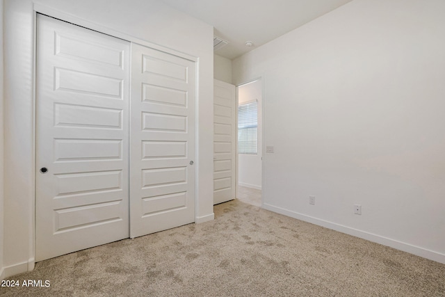 unfurnished bedroom featuring light colored carpet and a closet