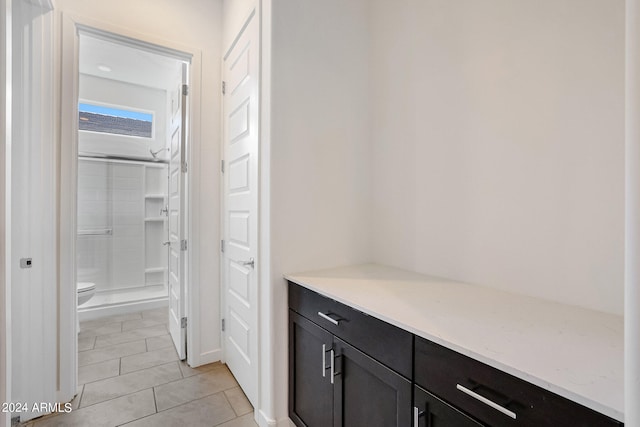 interior space featuring walk in shower, toilet, vanity, and tile flooring