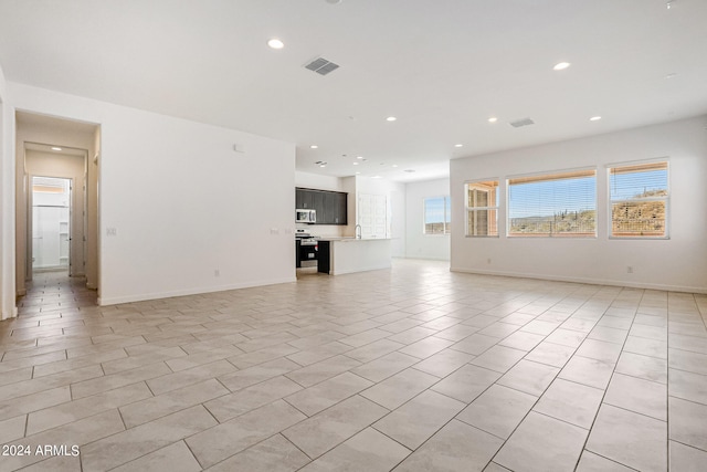 unfurnished living room with sink and light tile flooring