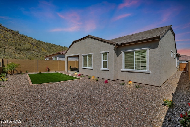 back house at dusk with a patio area and a mountain view