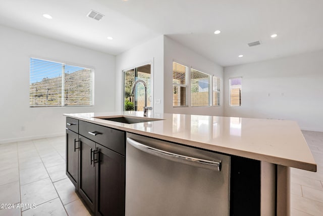 kitchen with stainless steel dishwasher, sink, a center island with sink, and light tile flooring