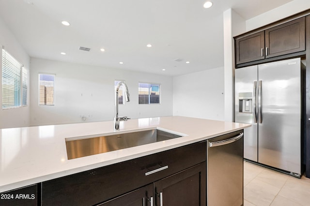 kitchen featuring appliances with stainless steel finishes, sink, dark brown cabinets, and light tile floors