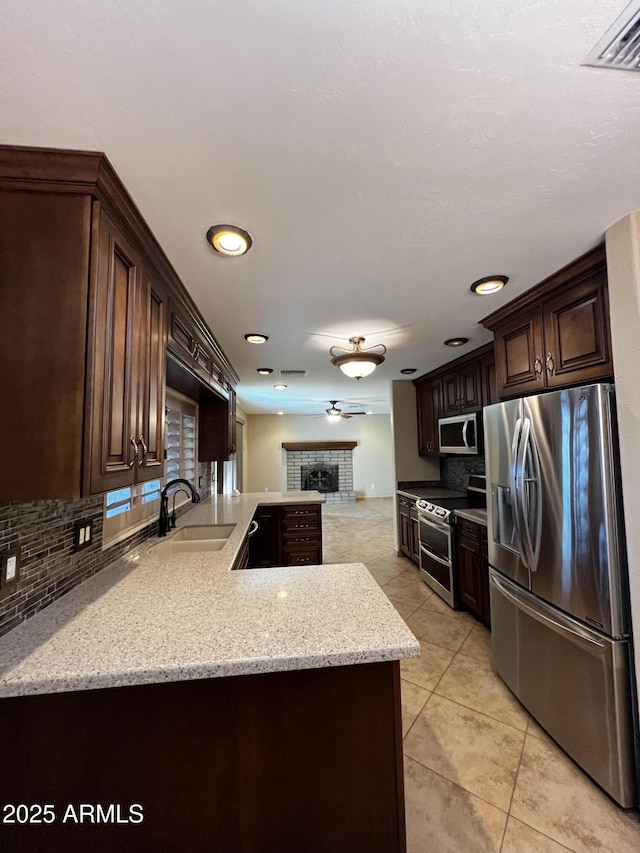 kitchen featuring dark brown cabinetry, sink, stainless steel appliances, and light stone countertops