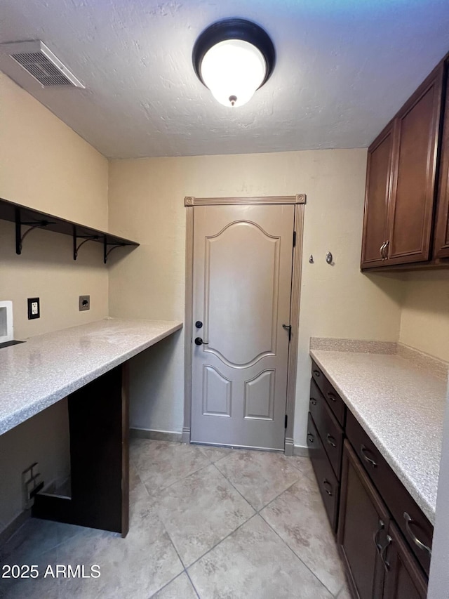 washroom with electric dryer hookup, cabinets, and a textured ceiling