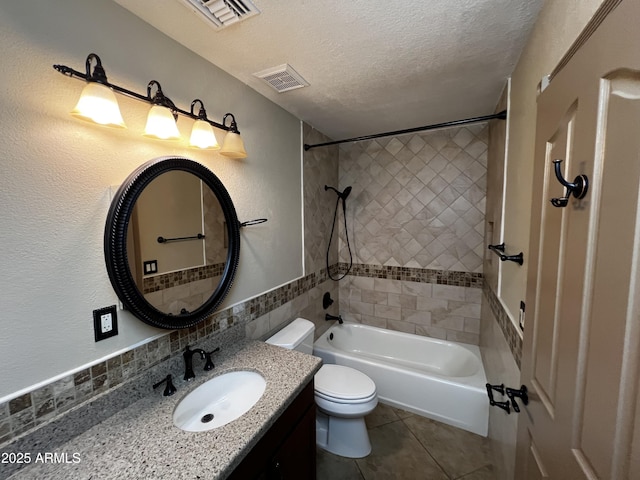 full bathroom with tile patterned floors, toilet, tiled shower / bath, a textured ceiling, and vanity