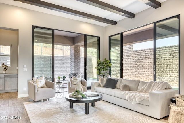 living area featuring beamed ceiling, baseboards, and wood finished floors