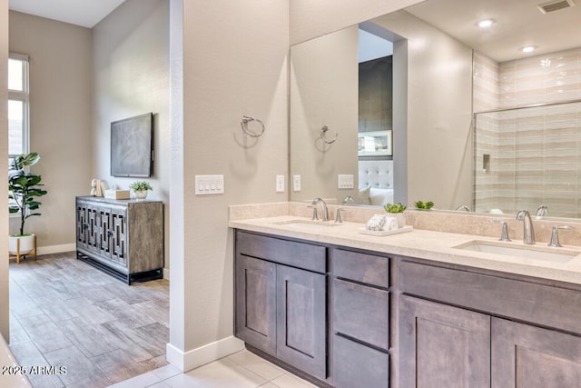 bathroom with a sink, double vanity, a shower stall, and tile patterned flooring