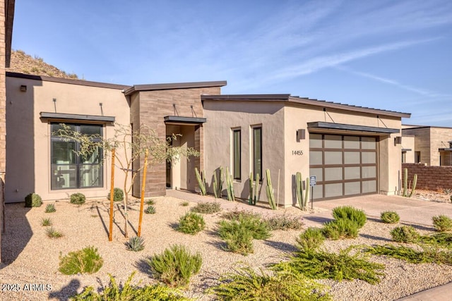 view of front of home with stucco siding, driveway, and a garage